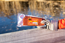 Load image into Gallery viewer, Hot salami stix held by hand by water.