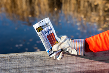 Load image into Gallery viewer, Original munchies held by gloved hand in front of water.