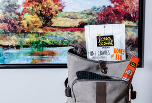Honey bbq mini-craves in backpack in front of painting.